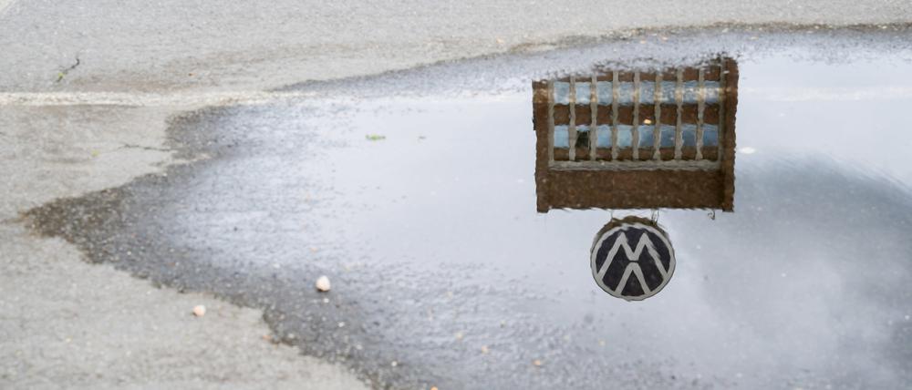Das Markenhochhaus auf dem Gelände vom VW-Werk Wolfsburg spiegelt sich in einer Pfütze.