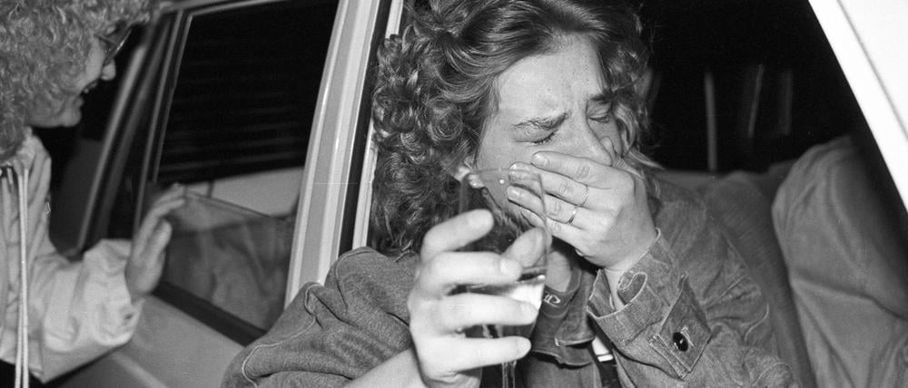 Öffnung der Grenzen zwischen der DDR und der BRD: Überwältigte DDR-Bürgerin im Trabi mit Sekt an einem Grenzübergang in Berlin.