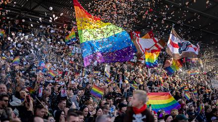 Fans des FC St. Pauli mit Regenbogen-Fahnen und Konfetti beim Spiel gegen den VfL Wolfsburg.