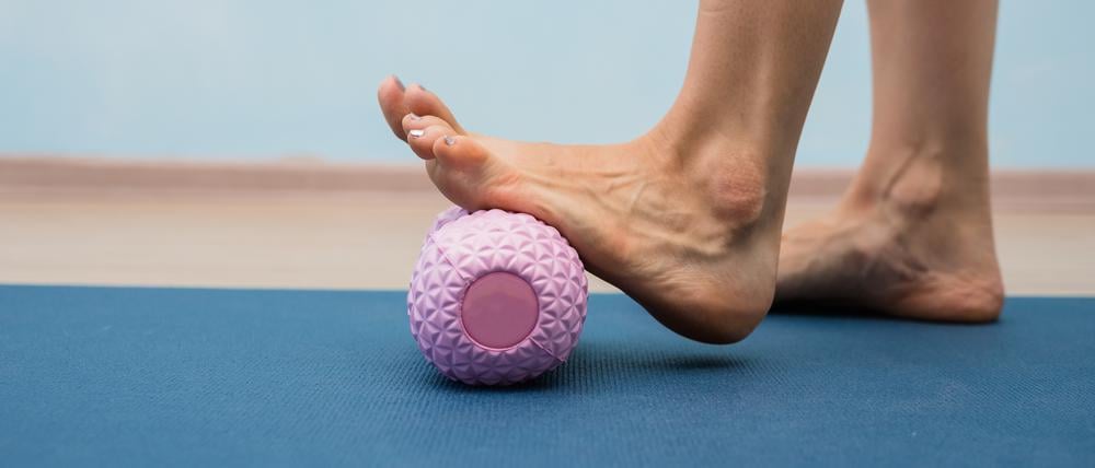 Eine Frau nutzt eine Massagerolle für ihren Fuß