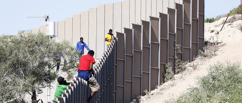 Migranten klettern im Jahr 2023 über einen Zaun auf der Insel Lampedusa.