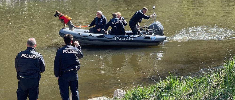 Polizisten suchen ein Gewässer ab.