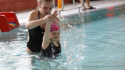 Eine Schwimmlehrerin bei einer Übung mit einem Mädchen.