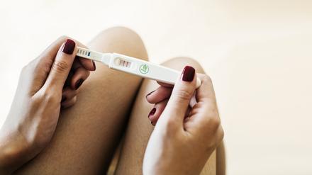 Eine Frau hält einen Schwangerschaftstest in den Händen.