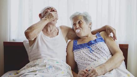 Ein älteres Paar sitzt gemeinsam gut gelaunt im Bett.