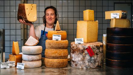 Gereifter Rohmilchkäse (Cheddar, Parmesan, Deichkäse) und Mitarbeiterin Florence Heaps bei „Alte Milch“ in der Kreuzberger Markthalle Neun.