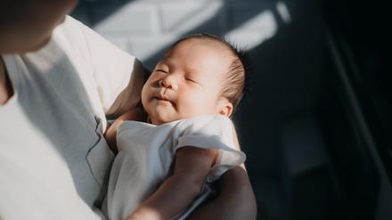 Ein asiatisches Baby schläft im Arm seiner Mutter. Nicht überall ist das Geschlecht eines Kindes dem Zufall überlassen.