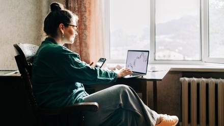 Eine junge Frau schaut sich Aktienkurse auf ihrem Laptop an.