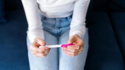 Eine junge Frau hält einen Schwangerschaftstest in der Hand.