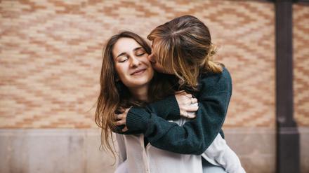 Zwei Frauen umarmen und küssen sich.