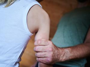 Ein Mann hält ein Kind fest am Arm (gestellte Szene).