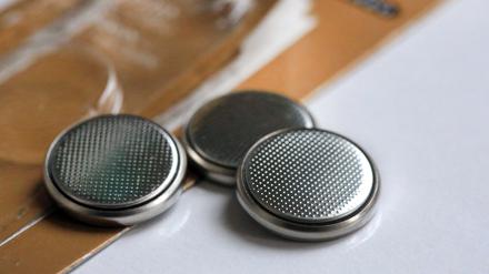 Mehrere Knopfzellbatterien liegen neben ihrer Verpackung auf einem Tisch.