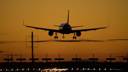 Ein Flugzeug landet auf dem Flughafen Berlin-Brandenburg (BER) vor rotem Abendhimmel.