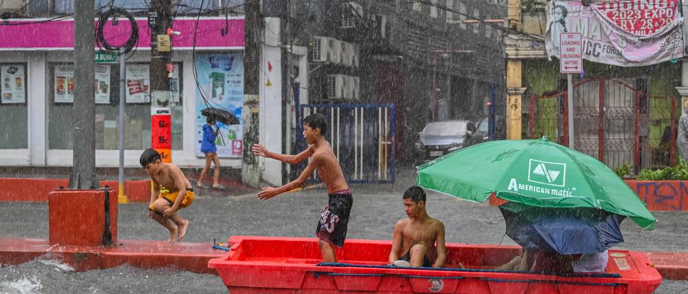 Nach starkem Regenfall spielen Kinder mit einem verlassenen Rettungsboot in Quezon City, ein der eingemeindeten Metropolen von Manila, der Hauptstadt der Philippinen.
