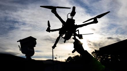 Ein DLR-Mitarbeiter hält eine Drohne vor einem Fahrzeug zur Drohnendetektion auf dem Gelände vom DLR Deutsches Zentrum für Luft- und Raumfahrt bei der Eröffnung des Drohnentestfelds Flybots.