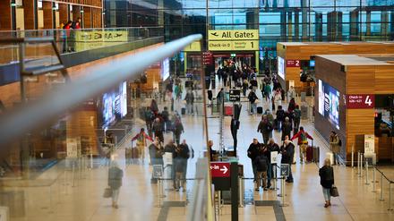 Zahlreiche Menschen gehen am Flughafen BER zur Sicherheitskontrolle.