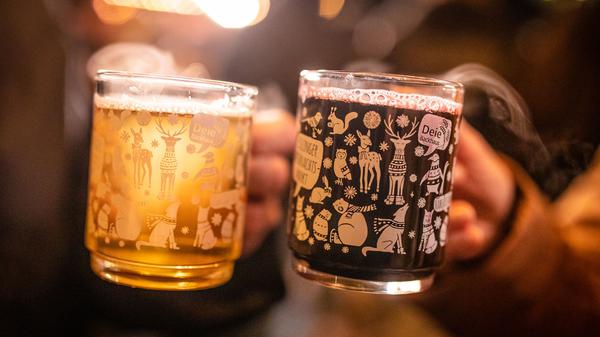 Ein Pärchen stößt auf dem Esslinger Weihnachtsmarkt mit weißem und rotem Glühwein an.