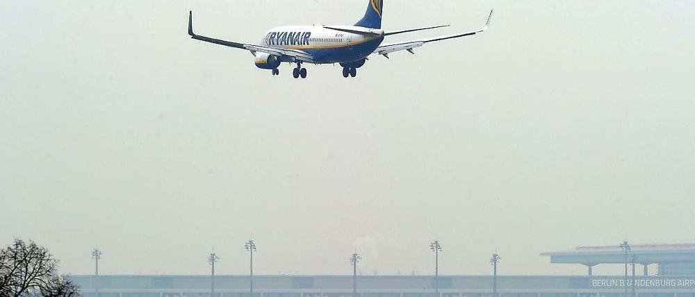 Eine Maschine der Fluggesellschaft Ryanair landet auf dem Flughafen in Schönefeld. Im Hintergrund ist der noch nicht eröffnete BER zu sehen.