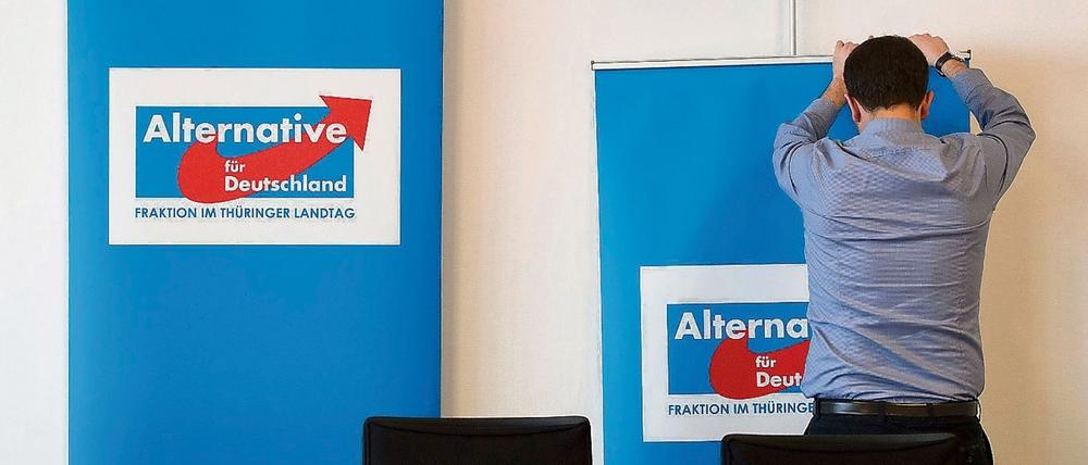 Ein Mann rollt am 09.04.2015 in Erfurt nach einer Pressekonferenz der Thüringer AfD-Landtagsfraktion ein Poster mit dem Logo der Partei zusammen.