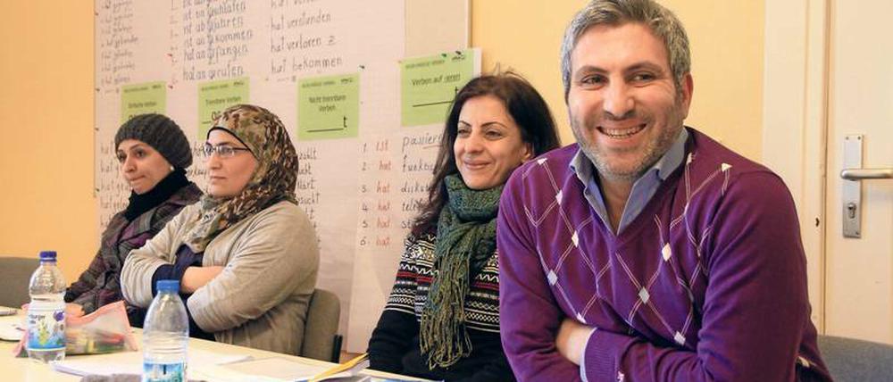 Drei Frauen und ein Mann sitzen in einem Klassenraum an einem Tisch.