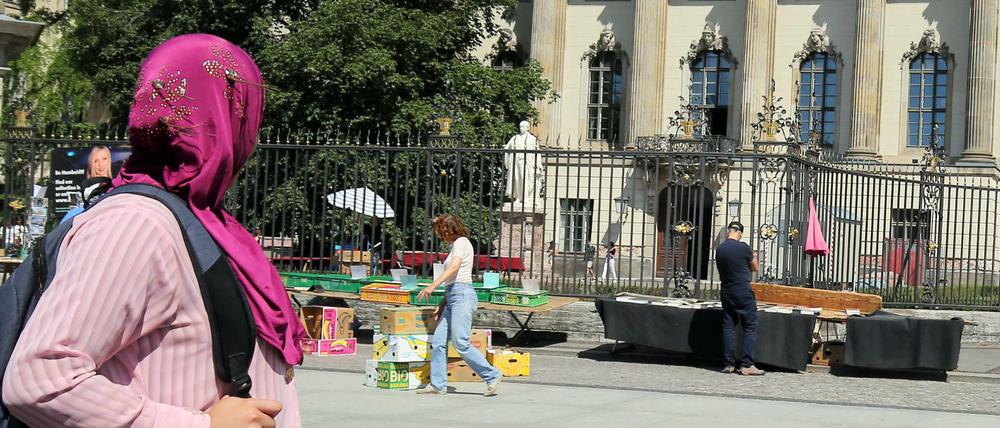 Eine Frau mit Kopftuch geht an der Humboldt-Universität an der Straße Unter den Linden in Berlin vorbei.