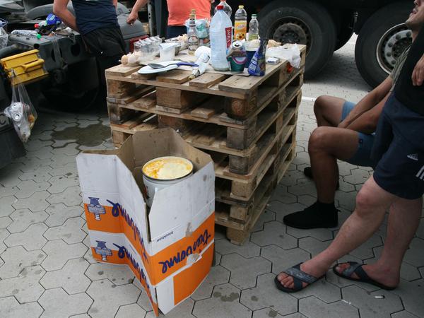 Tafelrunde. Ein Tisch aus Europaletten, den Gaskocher mit einem Umzugskarton abgeschirmt - die Verpflegung der Fahrer ist oft spartanisch.