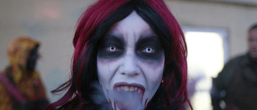 Eine Frau, verkleidet als professioneller Erschrecker für das Halloween Horror Fest, raucht eine Zigarette im Movie Park Germany in Bottrop.