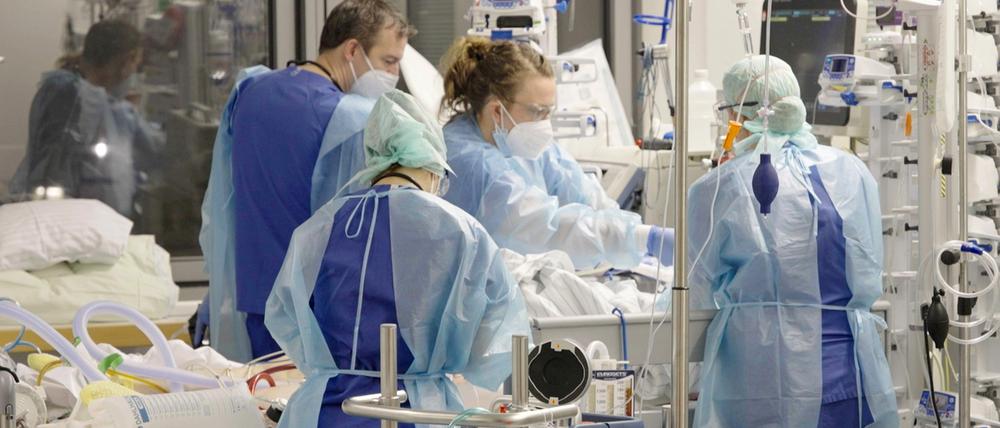 Ärztinnen, Ärzte und Pflegende arbeiten auf der Corona-Intensivstation der Charité am Bett einer Patientin.