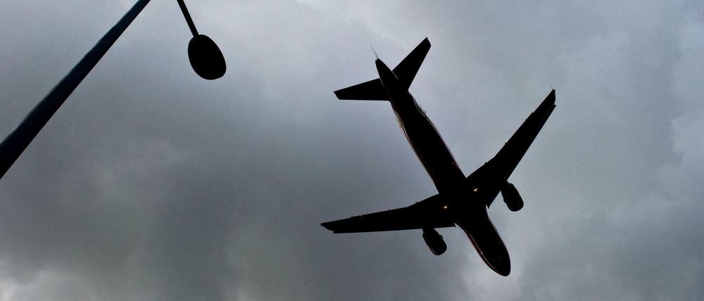 Flugzeug vor dunklen Wolken am Himmel.
