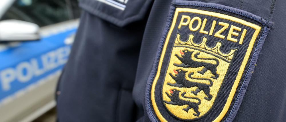 Das Wappen der baden-württembergischen Polizei ist vor der Polizeidirektion neben einem Polizeifahrzeug zu sehen.