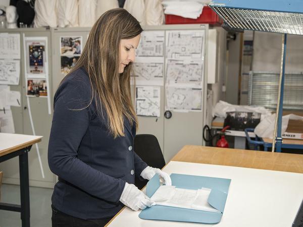 Die leitende Restauratorin Iris Lasetzke hüllt den Zettel in Seidenpapier.