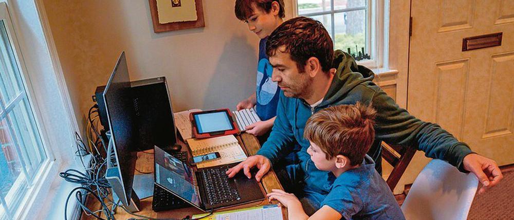 Vater lernt mit Kindern zu Hause.