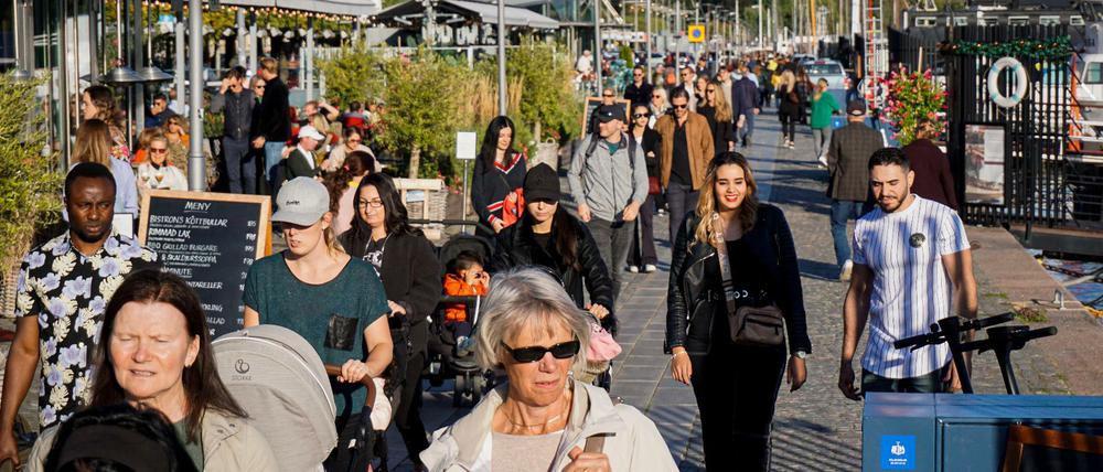 Schönes Wetter und viel los: Menschen laufen an einem sonnigen Tag durch Stockholm.