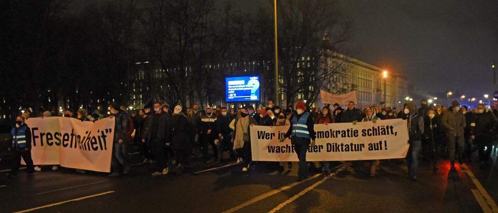Teilnehmer einer Demonstration gegen die Corona-Maßnahmen gehen mit Transparenten durch die Stadt.