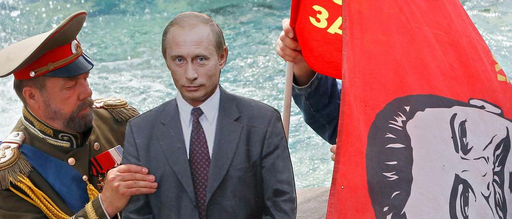Starke oder schwache Führer machen die Geschichte, glaubt Putin. Hier ein als Zar verkleideter Mann mit einem Pappbild von Putin und Fahren mit Stalins Konterfei (Archivbild).