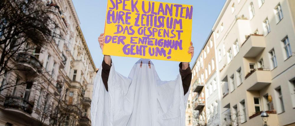 Eine Aktivistin im Gespensterkostüm hält ein Protestschild nahe dem Organisationsbüro des Volksbegehrens ´Deutsche Wohnen & Co. enteignen» in die Kamera.