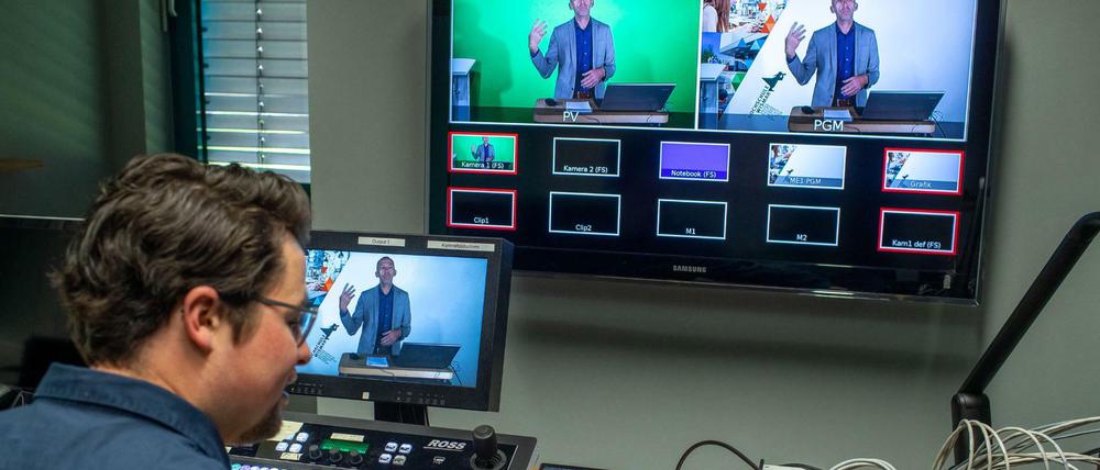 Ein Universitätsmitarbeiter steuert die digitale Aufnahme einer Vorlesungen in einem Uni-Hörsaal.