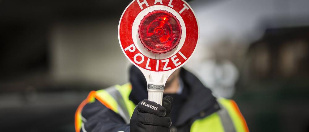 Ein Polizeibeamter hält eine Polizeikelle im Rahmen einer Verkehrskontrolle in der Hand.