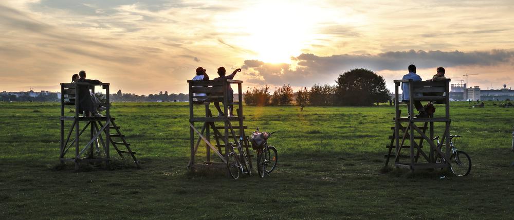 Auf Hochsitzen geniessen Besucher am Tempelhofer Feld den Sonnenuntergang.