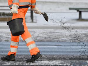 ARCHIV - 05.01.2017, Brandenburg, Potsdam: Ein Arbeiter in Schutzkleidung ist auf einem Gehweg in Potsdam mit Streuarbeiten beschäftigt. (zu dpa : «Glatteis und Verkehrsstörungen zum Wochenbeginn befürchtet») Foto: Ralf Hirschberger/dpa-Zentralbild/dpa +++ dpa-Bildfunk +++