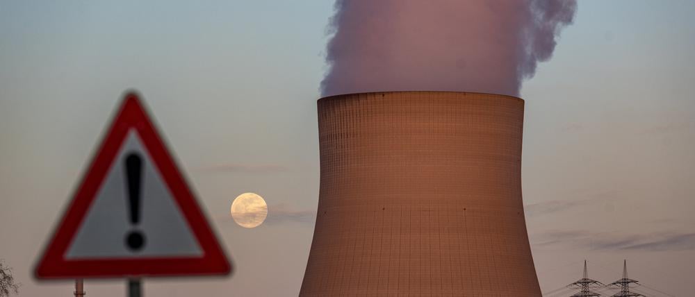 Bayern, Essenbach: Wasserdampf steigt aus dem Kühltum des Kernkraftwerks Isar 2 hinter einem Warnschild.