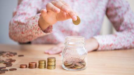 Eine Frau wirft Münzen in ein Glas. Ende Oktober rufen die Banken wieder zum Weltspartag auf.