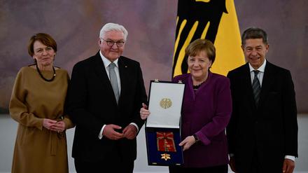 Frank-Walter Steinmeier überreicht Angela Merkel den Orden. Daneben stehen ihr Ehemann Joachim Sauer (rechts) und Steinmeiers Ehefrau Elke Büdenbender (links).