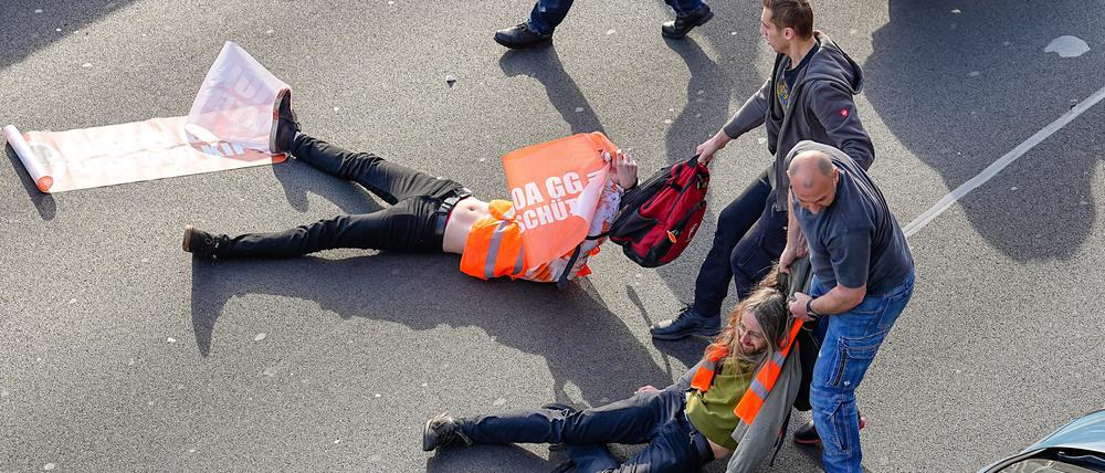 Aufgebrachte Verkehrsteilnehmer, die durch die Aktivisten aufgehalten werden, versuchen die Protestler von der Straße zu ziehen.