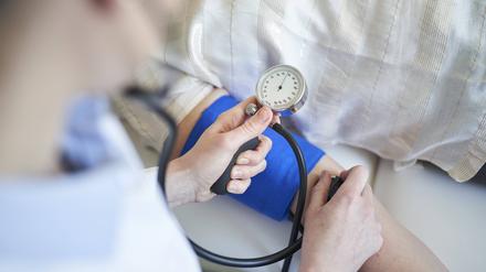 Close-up of doctor taking blood pressure of patient in medical practice model released Symbolfoto PUBLICATIONxINxGERxSUIxAUTxHUNxONLY PNEF01501