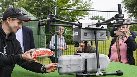 Eine Drohne wird bei der Betriebseröffnung vom Drohnen-Lieferservice ·Marktschwalbe· mit einem Bäckerbrot beladen.