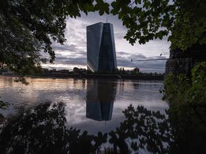 Die Zentrale der Europäischen Zentralbank (EZB) in Frankfurt spiegelt sich im Abendlicht im Main.