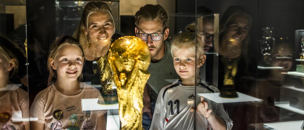 Eine Familie bewundert den deutschen Siegerpokal der Fußball-WM von 2014 in der Schatzkammer des Dortmunder Fußballmuseums.