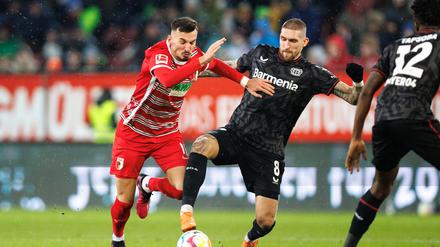 Mergim Berisha vom FC Augsburg (l) und Robert Andrich von Bayer Leverkusen im Zweikampf um den Ball.