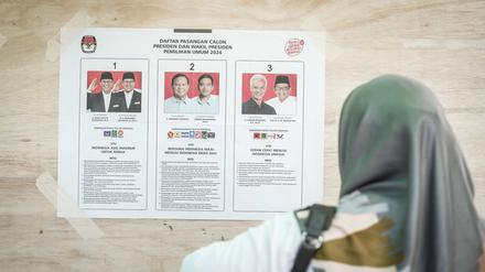 Eine Frau schaut sich eine Kandidatenliste für die Wahl in Indonesien an. Der Ex-General Prabowo könnte die Wahl mit hohem Vorsprung gewinnen. 